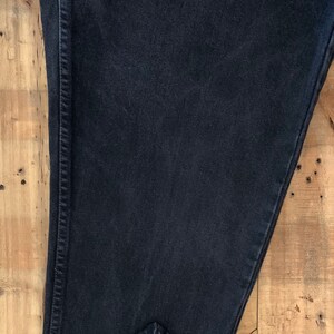 May include: A pair of black denim jeans folded in half, showing the inside seam and the hem.