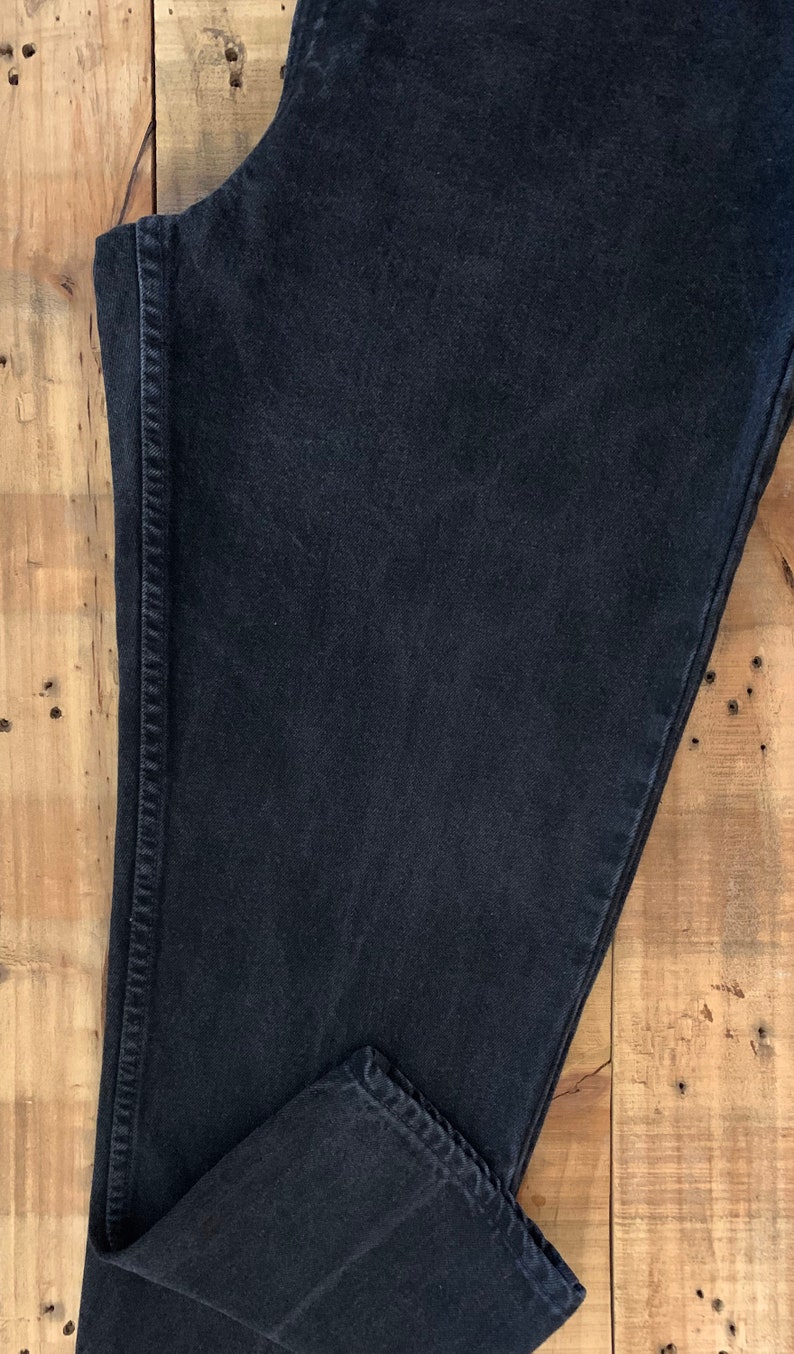 May include: A pair of black denim jeans folded in half, showing the inside seam and the hem.