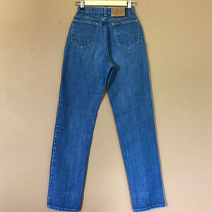 May include: A pair of blue denim jeans with a brown leather Lee label on the back pocket.