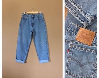 May include: A pair of light blue denim jeans with a cuffed hem. The jeans have a Levi's logo patch on the back pocket. The jeans are a relaxed fit and have a high waist.