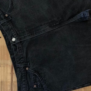 May include: A pair of black denim jeans with a button fly and a single back pocket.