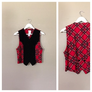 May include: A red and black plaid vest with a black velvet front panel. The vest has a button closure and a pointed collar.