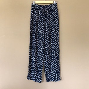 Puede incluir: Pantal&oacute;n negro con estampado floral blanco. El pantal&oacute;n tiene una cintura el&aacute;stica y un cord&oacute;n.