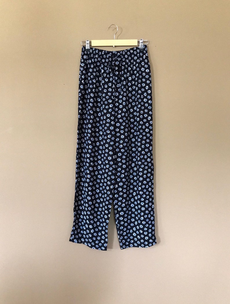 Puede incluir: Pantal&oacute;n negro con estampado floral blanco. El pantal&oacute;n tiene una cintura el&aacute;stica y un cord&oacute;n.