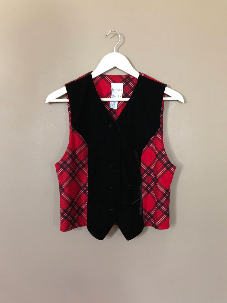 May include: A black velvet vest with a red and black plaid pattern on the sides. The vest has a button closure and a V-neck.