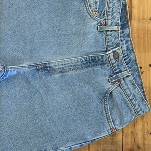 May include: Light blue denim jeans with classic five-pocket styling. The jeans feature copper rivets, a button closure, and a straight leg design. The garment is made of durable denim fabric.