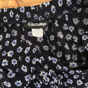 Puede incluir: Pantal&oacute;n azul marino con estampado floral blanco y cintura con cord&oacute;n. El pantal&oacute;n tiene una etiqueta que dice "Elastounge" y "Medium".