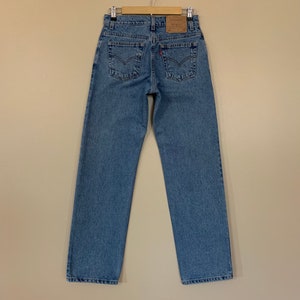 May include: A pair of blue denim jeans with a brown leather Levi's patch on the back.
