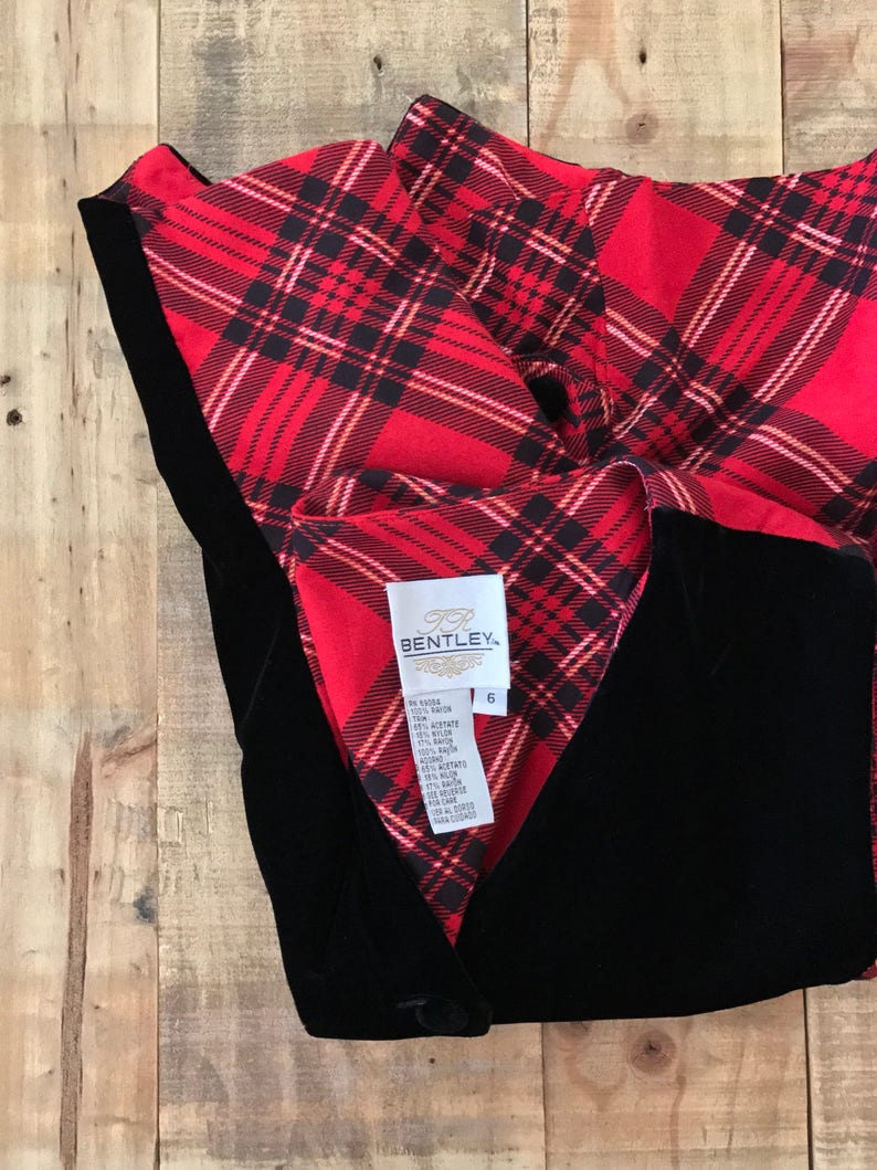 May include: Black velvet vest with a red and black plaid lining. The vest has a button closure and a label that reads "Bentley" with size 6.