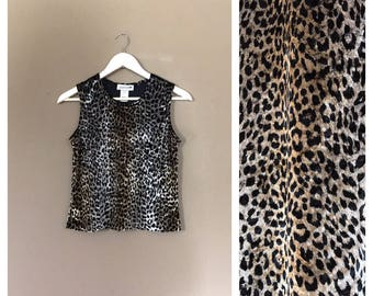 May include: A sleeveless top with a leopard print pattern. The top is made of a soft, silky fabric and has a relaxed fit.