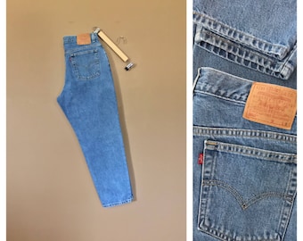 May include: Light blue denim jeans with a brown leather Levi's patch on the back pocket. The jeans have a relaxed fit and a straight leg.