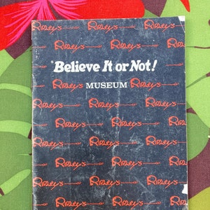 Puede incluir: Un folleto negro y rojo para el Museo Ripley's Believe It or Not! en St. Augustine, Florida. El folleto está cubierto con un patrón repetido del logotipo de Ripley's.