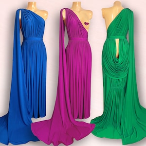 Könnte beinhalten: Drei drapierte One-Shoulder-Kleider in leuchtenden Farben: Königsblau, Magenta und Smaragdgrün. Jedes Kleid hat ein fließendes, bodenlanges Design mit drapiertem Oberteil und einer langen, eleganten Schleppe. Die Kleider werden auf Schaufensterpuppen präsentiert.