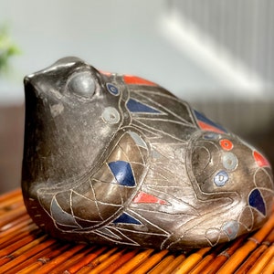 May include: A gray ceramic frog figurine with geometric patterns in shades of blue, red, and white.