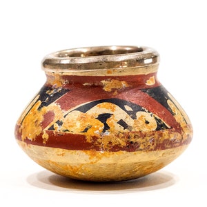May include: A small, round, ceramic pot with a silver rim. The pot is decorated with a geometric pattern in red, black, and yellow.