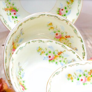 May include: Three white porcelain bowls with floral designs. The bowls are stacked on top of each other, with the largest bowl on the bottom and the smallest bowl on top. The bowls have a delicate floral pattern in shades of pink, blue, and green.