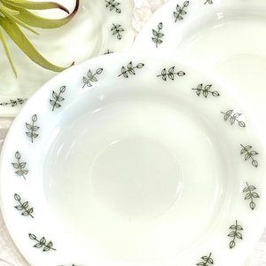 May include: A set of three white ceramic plates with a green leaf design around the edge.
