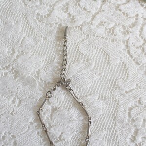 May include: A silver chain necklace with a lobster clasp closure. The chain is made of small, linked bars.