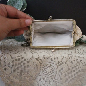 May include: A small, white beaded coin purse with a gold metal frame and a chain attached. The purse is open and the inside is lined with white fabric.