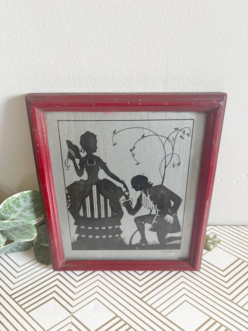 Puede incluir: Enmarcado arte de silueta con un marco rojo desgastado. La imagen en blanco y negro muestra a un hombre arrodillado ante una mujer. La obra de arte representa una escena rom&aacute;ntica. El marco es de forma cl&aacute;sica, ideal para decoraci&oacute;n vintage.