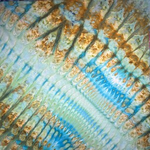 May include: Abstract textile art with a tie-dye pattern. The design features diagonal stripes in shades of blue, green, and brown. The fabric has a textured appearance, with the colors blending and overlapping to create a unique visual effect.