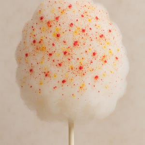 May include: A cloud of white candy floss on a wooden stick, dotted with small red and yellow sprinkles. The background is a soft, neutral colour.