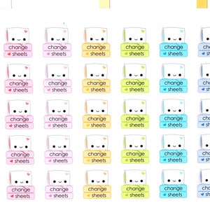 Op de afbeelding: Een vel met kleurrijke stickers waarop een cartoonfiguur een stapel lakens vasthoudt. De stickers zeggen "change sheets" en zijn in verschillende kleuren, waaronder roze, blauw, geel en groen.