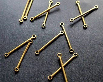 May include: A collection of small, gold-colored metal connectors with a bar shape and circular holes at each end. The connectors are scattered on a dark surface, with some overlapping. These jewelry findings are ideal for DIY jewelry making.