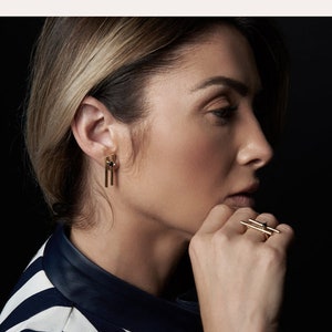 May include: A woman wearing a black and white striped shirt with gold bar earrings and a gold bar ring. The text "Make It A SET" and "Bar Ring + Bar Earrings" is displayed above the image. The text "Jewelry set" is displayed in the top left corner of the image. The text "The Morning After" is displayed in the top right corner of the image.