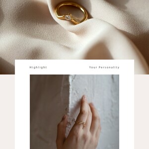 May include: A gold ring with a single, clear gemstone set in the center. The ring is shown on a hand and on a piece of fabric.