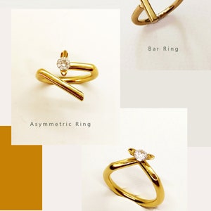 May include: Three gold rings with a single clear stone set in each. The rings are labeled "Bar Ring", "Asymmetric Ring", and "Classic Ring".