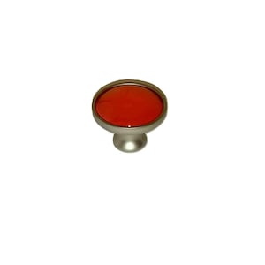 May include: A round, red, glass knob with a silver base. The knob is a decorative hardware piece for furniture.