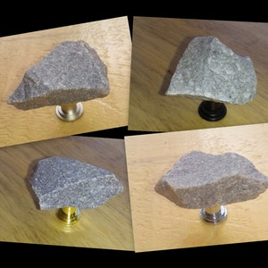 May include: Four different stone cabinet knobs with various metal finishes. The knobs are made of rough, grey stone and have a unique, natural shape. The metal finishes include silver, black, gold, and chrome.