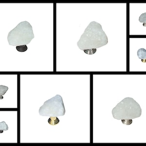 May include: A selection of cabinet knobs with a natural, irregular white stone top. The knobs have metal bases in bronze, silver, and gold finishes. The stone has a crystalline texture.