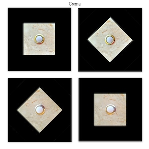 Peut inclure: Quatre carreaux carrés avec un motif de marbre de couleur crème et un bouton blanc au centre. Les carreaux sont disposés en grille 2x2. Les carreaux sont entourés d'un fond noir.