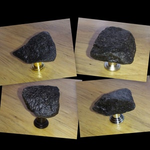 May include: Four black rock door knobs with different metal bases. The knobs are on a wooden surface.
