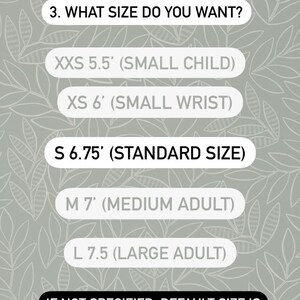 May include: A chart showing different sizes for a beaded scapular bracelet. The sizes are listed as XXS 5.5 inches (small child), XS 6 inches (small wrist), S 6.75 inches (standard size), M 7 inches (medium adult), and L 7.5 inches (large adult). The chart also states that the default size is 6.75 inches (standard size) if not specified. It also includes instructions on how to measure your wrist with a string and ruler and add 0.5 inches.