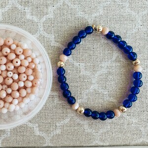 May include: A blue and gold beaded bracelet with a simple design. The bracelet is made with small, round beads in a dark blue color, interspersed with gold beads.