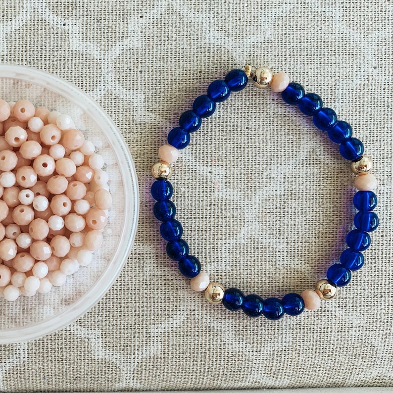 May include: A blue and gold beaded bracelet with a simple design. The bracelet is made with small, round beads in a dark blue color, interspersed with gold beads.
