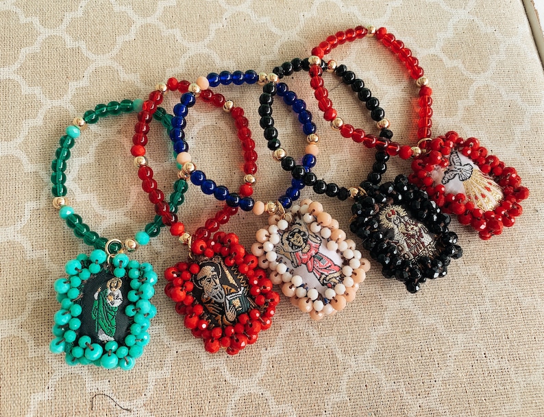 May include: Six colorful beaded bracelets with religious charms. Each bracelet features a different color of beads and a charm with a religious image.