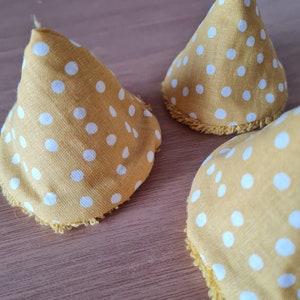 May include: Three yellow fabric cones with white polka dots and a white crocheted trim.