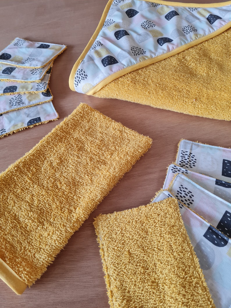 May include: A set of yellow hooded towels and washcloths with a geometric pattern. The towels and washcloths are made of a soft, absorbent material.
