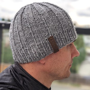 May include: A gray knitted beanie with a brown leather tag that says "2 Birds".