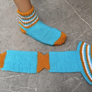 Puede incluir: Un par de calcetines de punto a rayas azules y naranjas. Un calcet&iacute;n est&aacute; en un pie y el otro est&aacute; puesto plano.