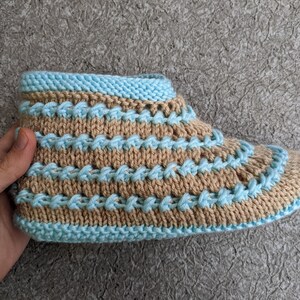 May include: Knitted slippers with a brown and light blue striped pattern. The slippers are made with a soft yarn and have a comfortable fit.