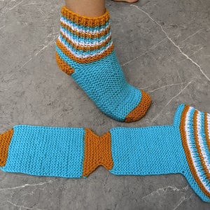 Puede incluir: Un par de calcetines de punto a rayas azules y naranjas. Un calcet&iacute;n est&aacute; en un pie y el otro est&aacute; puesto plano.