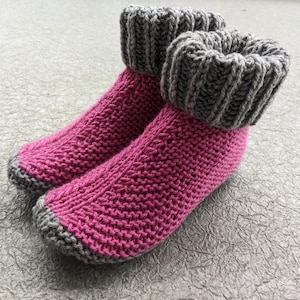 Peut inclure: Une paire de chaussettes de pantoufles en tricot rose avec des poignets en tricot gris.