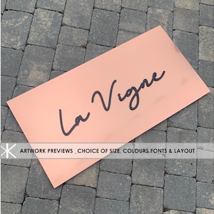 Könnte beinhalten: Ein rechteckiges rosa Schild mit dem Text "La Vigne" in schwarzer Kursivschrift. Das Schild befindet sich auf einer grauen Ziegelsteinfläche. Kunstwerke in der Vorschau - Auswahl von Größe, Farben, Schriftarten und Layout.