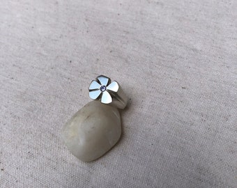 May include: A silver ring with a flower design and a small purple gemstone in the center.