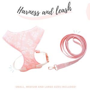 Pode incluir: Conjunto de arnês e trela rosa para animais de estimação. O arnês apresenta um design de pegadas e correias ajustáveis. A trela é da mesma cor e tem um fecho de metal. O texto na imagem diz "Harness and leash" e "Small, Medium and Large sizes included!"
